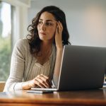 The Confidence Paradox: Navigating the Fine Line Between Confidence and Criticism Female sitting at her work desk looking away and thinking. Stressed woman taking a break to come up with solution.